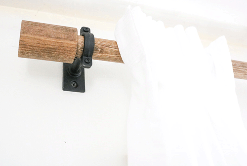 Wooden curtain rod close up in metal bracket on the wall