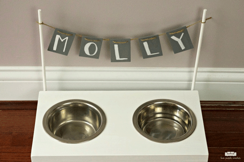 White dog bowl stand with attached banner that says Molly