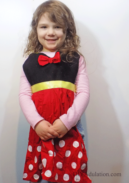 Little girl smiling and wearing Minnie Mouse apron