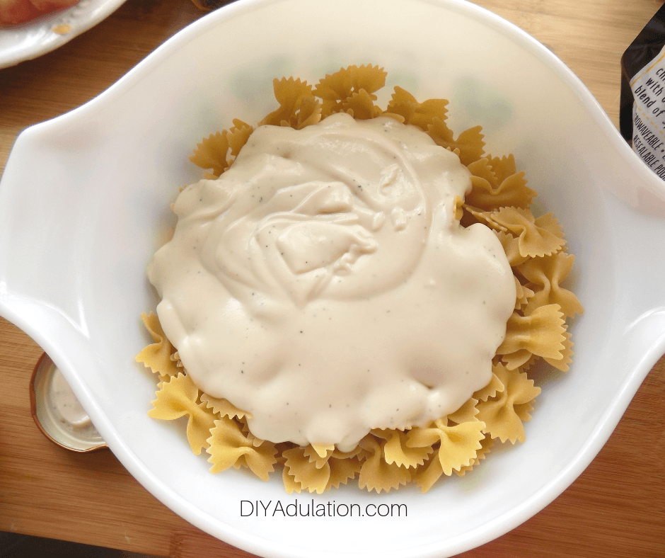 Alfredo Sauce in Bowl of Uncooked Bow Tie Pasta