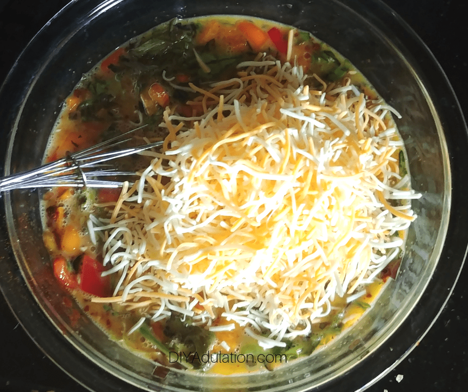 Cheese on Veggies Mixed with Eggs in Glass Mixing Bowl
