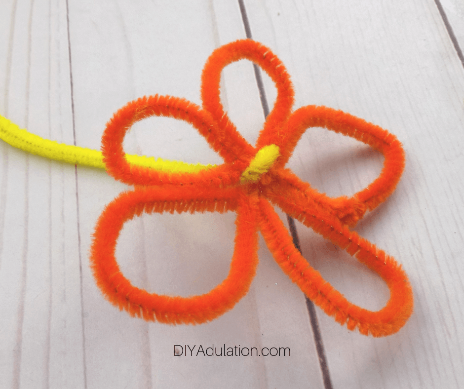 End of Yellow Pipe Cleaner Wrapped Around Center of Orange Pipe Cleaner Flower