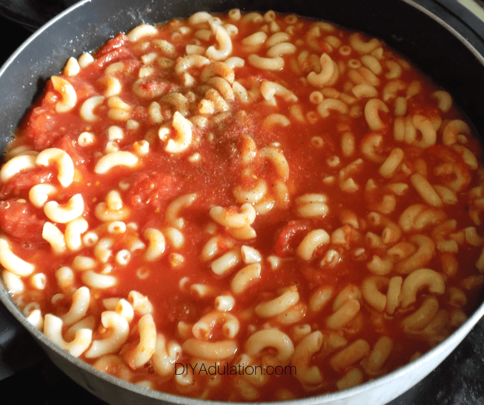 Salt and Pepper on Macaroni and Tomatoes in Pot