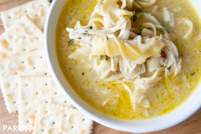 Close up of bowl of chicken noodle soup next to crackers