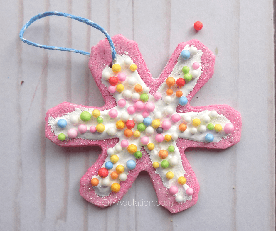 Pink Glittery Snowflake Cookie Ornaments Next to Sprinkles