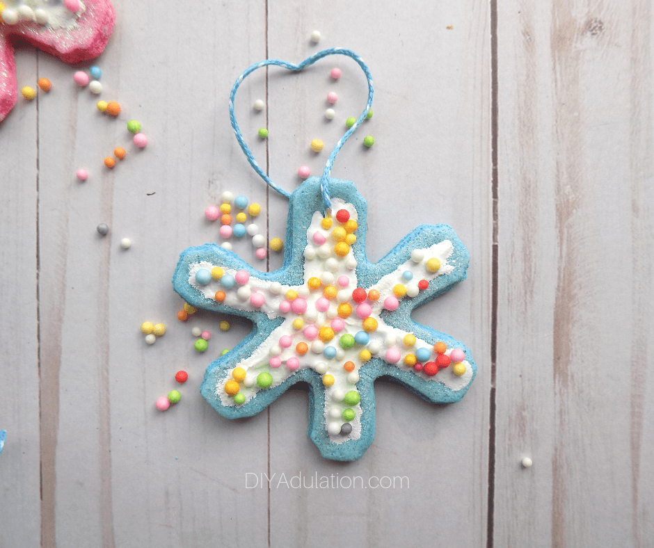 Teal Glittery Snowflake Cookie Ornaments Next to Sprinkles