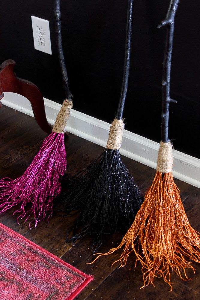 3 Glittery Witches Brooms next to wall